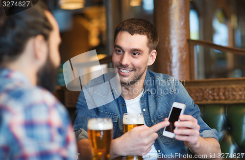 Image of male friends with smartphone drinking beer at bar