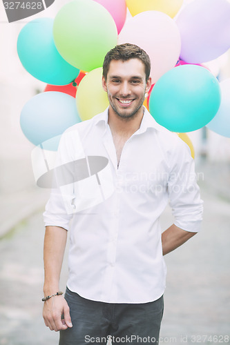 Image of man with colorful balloons in the city