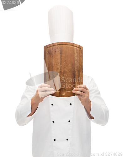 Image of male chef cook covering face with cutting board