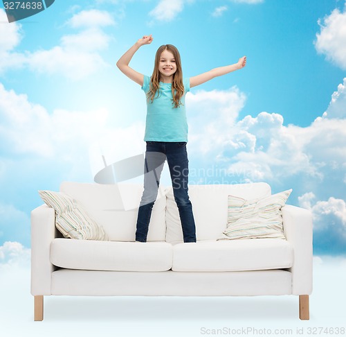 Image of smiling little girl jumping on sofa