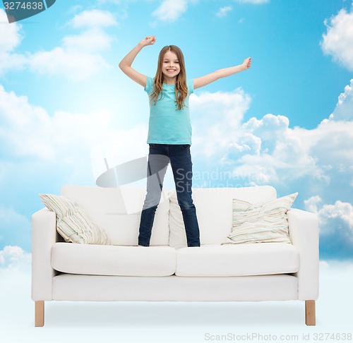 Image of smiling little girl jumping on sofa