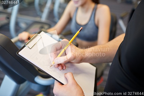 Image of close up of trainer hands with clipboard in gym