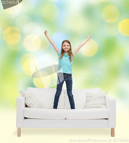 Image of smiling little girl jumping on sofa