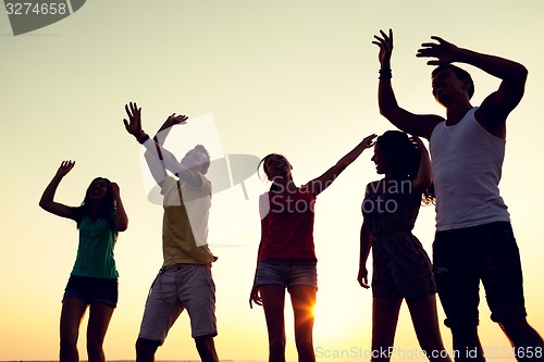 Image of smiling friends dancing on summer beach