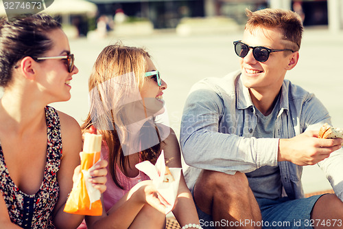 Image of group of smiling friends sitting on city square