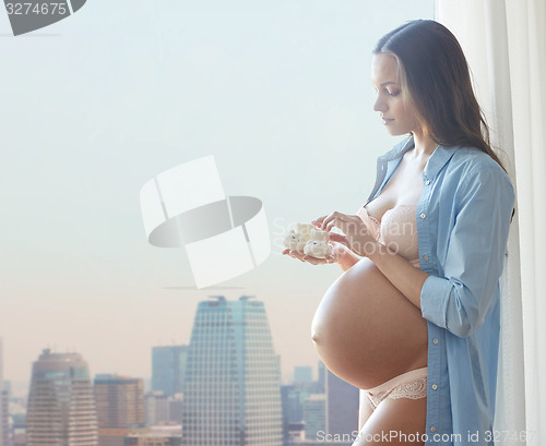 Image of happy pregnant woman with baby booties at home