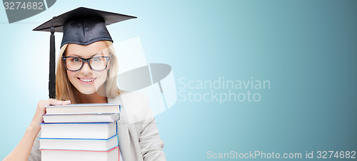 Image of happy student in mortar board cap with books