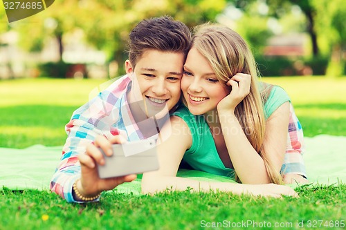 Image of smiling couple making selfie in park