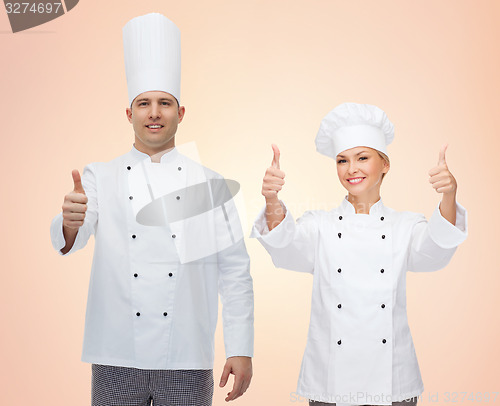 Image of happy chefs or cooks couple showing thumbs up