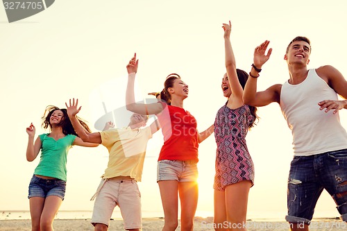 Image of smiling friends dancing on summer beach