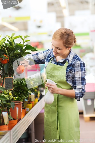 Image of happy woman touching mandarin tree in greenhouse