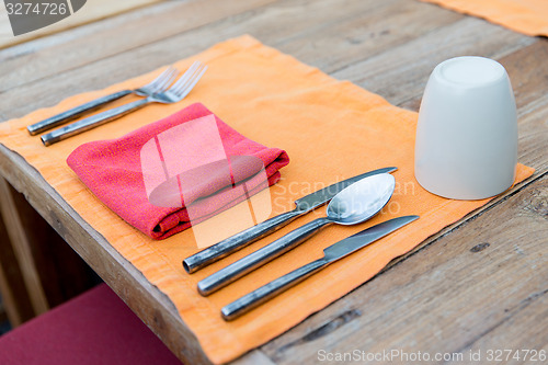 Image of close up of cutlery with glass and napkin on table