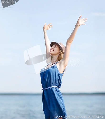 Image of girl with hands up on the beach