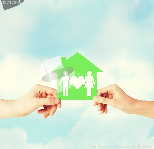 Image of hands holding green house with family