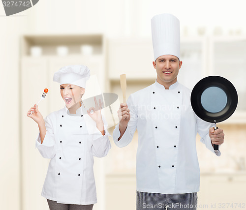 Image of happy male chef holding frying pan and spatula