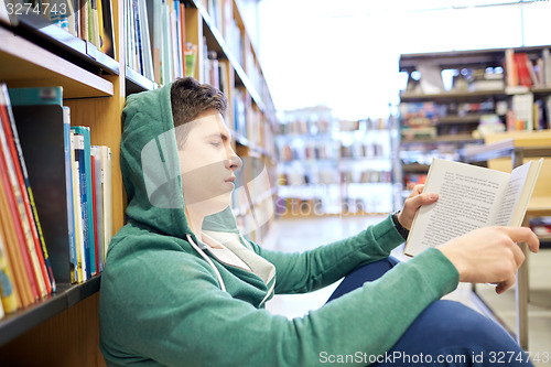 Image of student boy or young man reading book in library