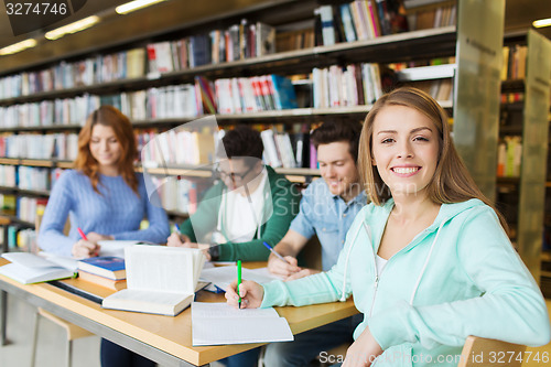 Image of happy student girl writing to notebook in library