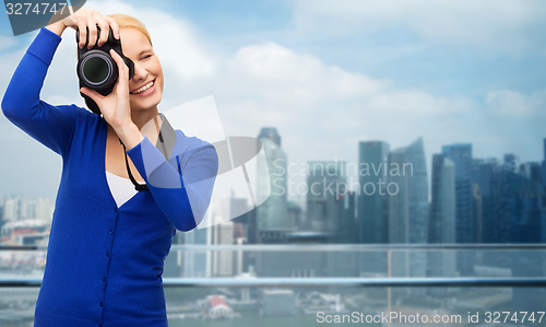 Image of smiling woman taking picture with digital camera