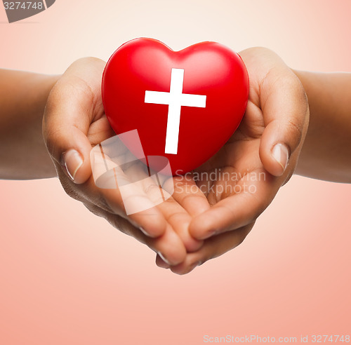 Image of close up of hands holding heart with cross symbol