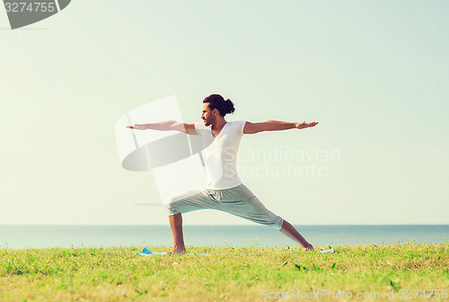 Image of smiling man making yoga exercises outdoors