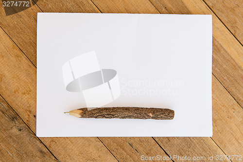 Image of white blank paper sheet with wooden pen on table 