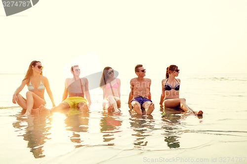 Image of smiling friends in sunglasses on summer beach