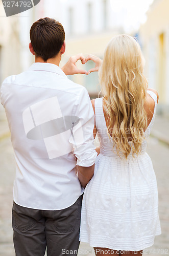 Image of romantic couple in the city making heart shape