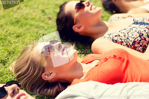 Image of group of smiling friends lying on grass outdoors