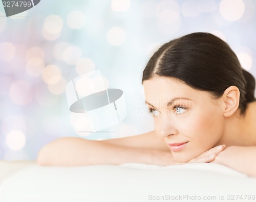 Image of happy beautiful woman lying on massage desk at spa