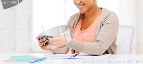 Image of african woman with smartphone in office