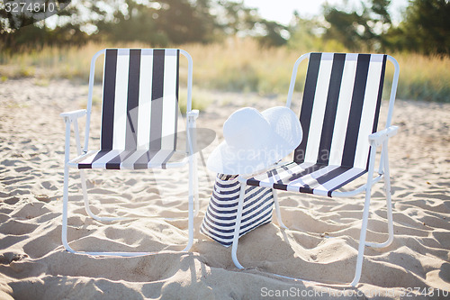 Image of two beach lounges with beach bag and white hat