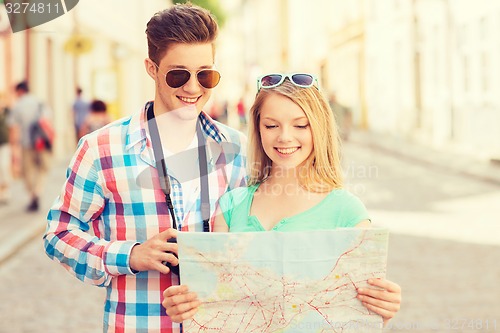 Image of smiling couple with map and photo camera in city