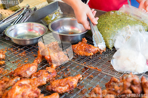 Image of close up of cook hand with tongs grilling chicken