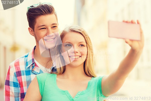 Image of smiling couple with smartphone in city