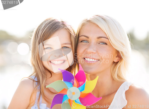 Image of happy mother and child girl with pinwheel toy