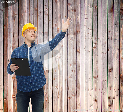 Image of smiling male builder in helmet with clipboard