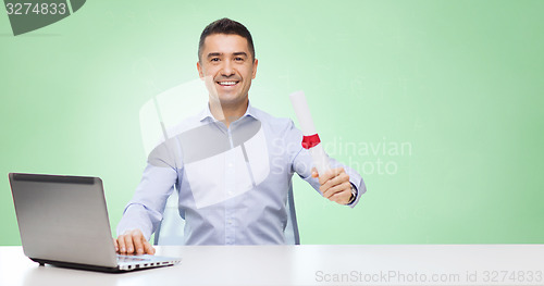 Image of smiling man with diploma and laptop at table