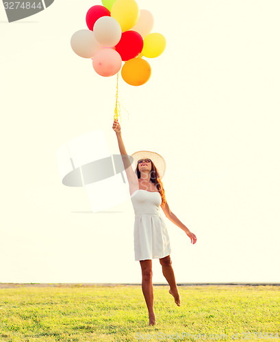 Image of smiling young woman in sunglasses with balloons