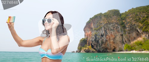 Image of woman in swimsuit taking selfie with smatphone