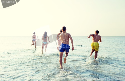 Image of smiling friends running on beach from back