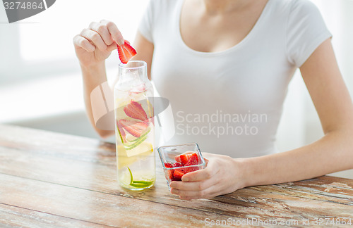 Image of close up of woman with fruit water in glass bottle