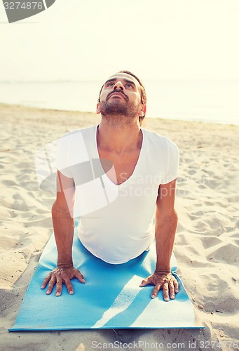 Image of man doing yoga exercises outdoors