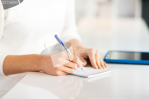 Image of close up of hands with pen writing to notepad