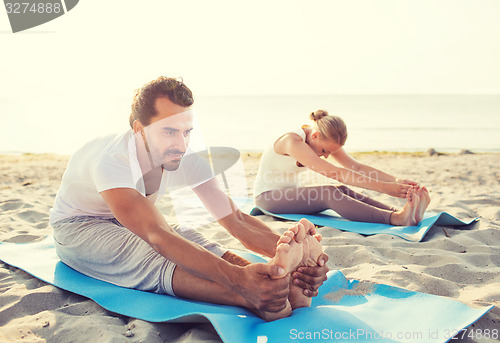 Image of couple making yoga exercises outdoors