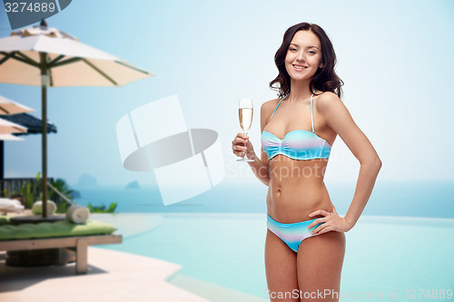 Image of happy young woman in swimsuit drinking champagne