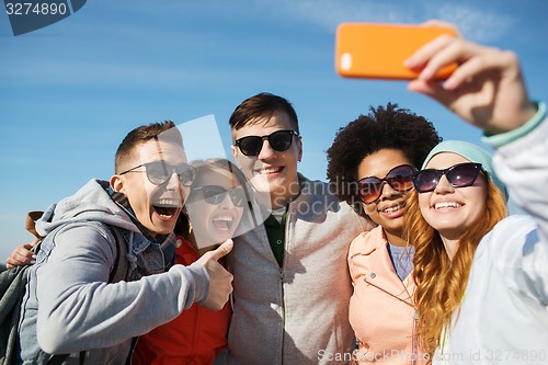 Image of smiling friends taking selfie with smartphone