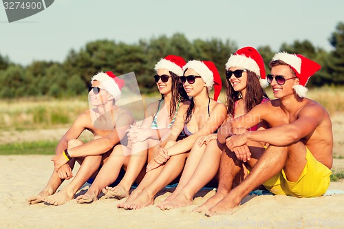 Image of group of friends in santa helper hats on beach