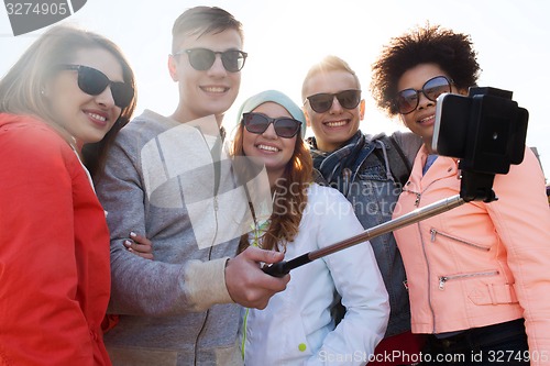 Image of friends taking selfie with smartphone on stick