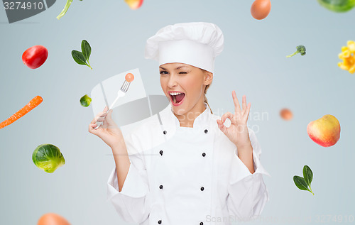 Image of smiling female chef with fork and tomato