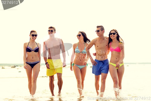 Image of smiling friends in sunglasses on summer beach